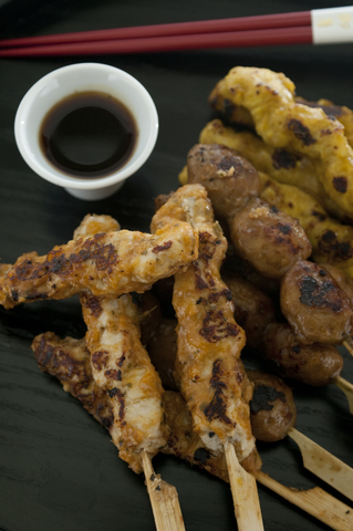 Chicken yakitori on skewers with dipping sauce.