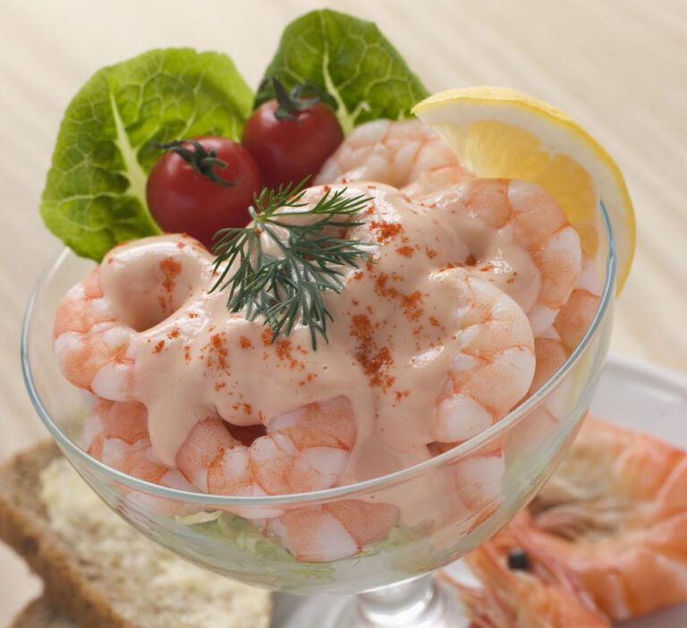 A bowl of classic prawn cocktail with cherry tomatoes and buttered bread.