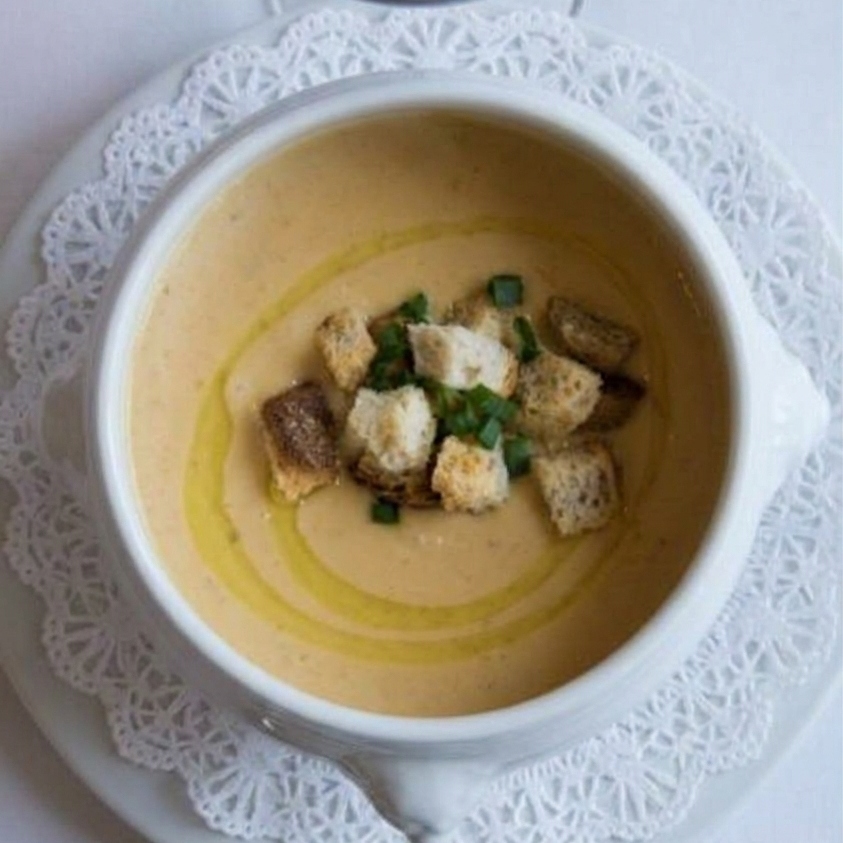 An ovehead view of parsnip apple soup with croutons on top.