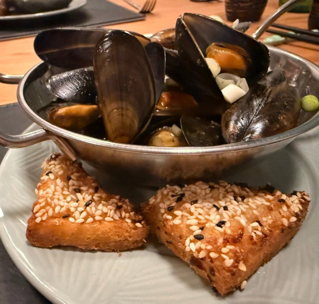 A bowl of mussels with homemade prawn toast.