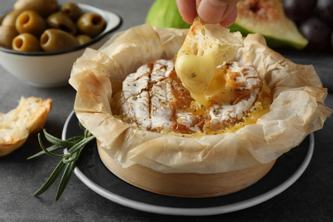 Baked Camembert in a wooden box with bread dipped into melted cheese