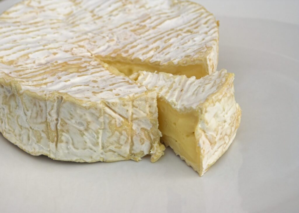 A wheel of Camembert cheese with one wedge cut out.