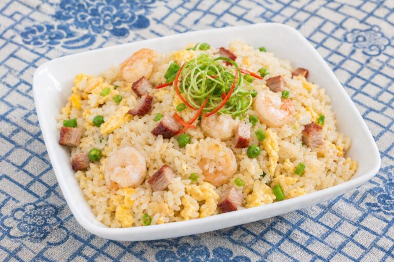 A dish of egg fried rice without soy sauce on a blue and white tablecloth.