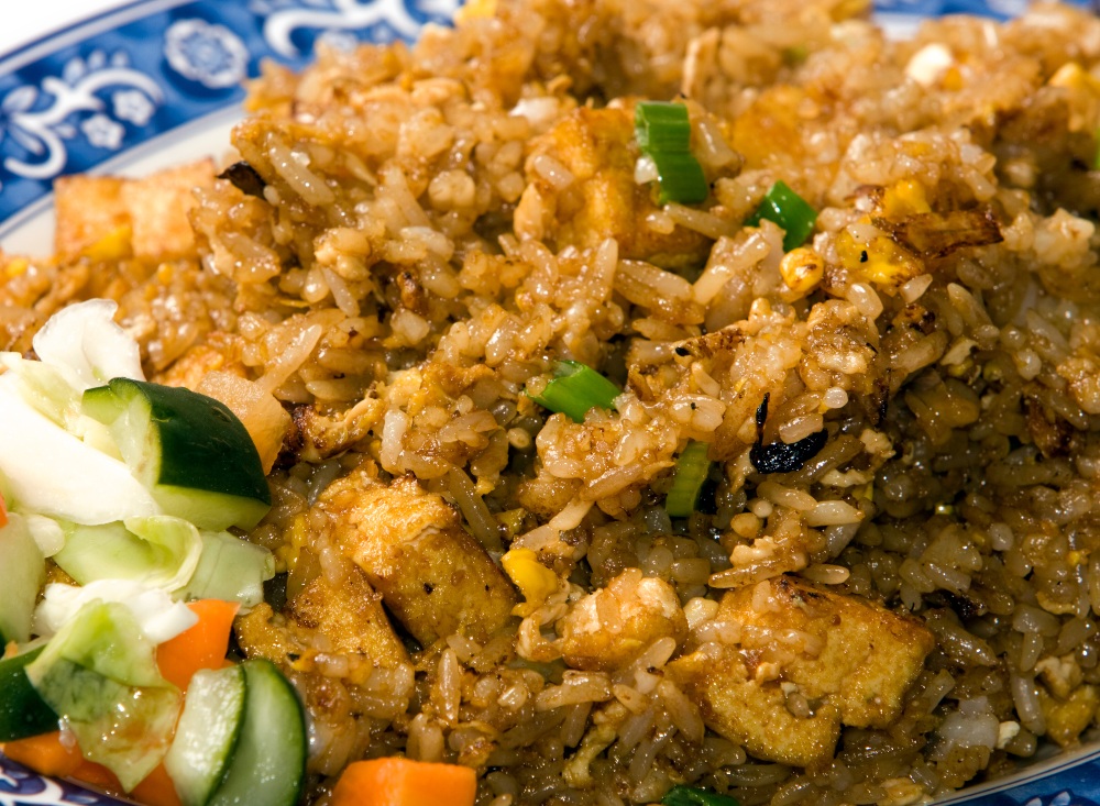 Close up of Indonesian nasi goreng on a blue and white plate, with a salad garnish.