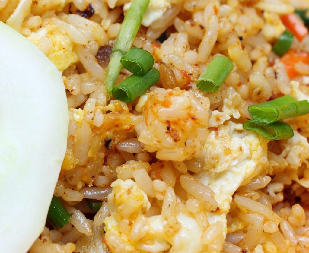 Fried rice with shrimp and chicken on a plate with a cucumber garnish.