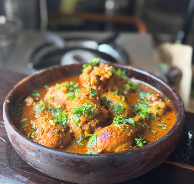 A bowl of chicken thigh curry with cilantro sprinkled on top.