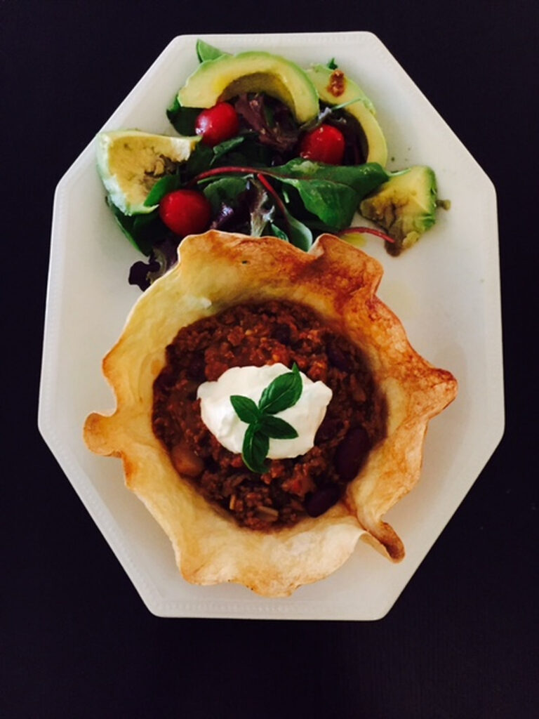 Bean-free diabetic chili in a crisp tortilla bowl with sour cream and fresh herbs.