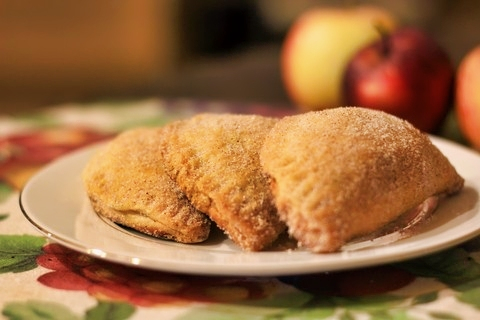 Golden pumpkin empanadas with cinnamon sugar on a plate.