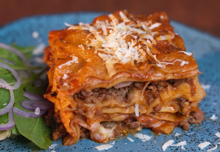 A slice of Ronzoni lasagna on a blue plate.