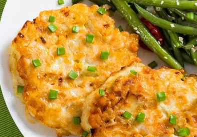 Crispy chicken fritters with a chive garnish on top.