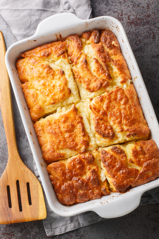 Baked butter swim biscuits in a baking dish with a spatula nearby.