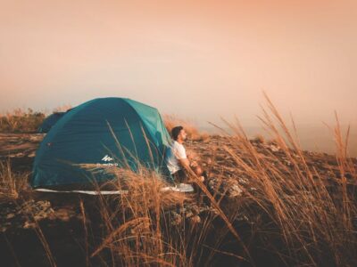 a man sitting in front of the tent thinking about the psychology of glamping