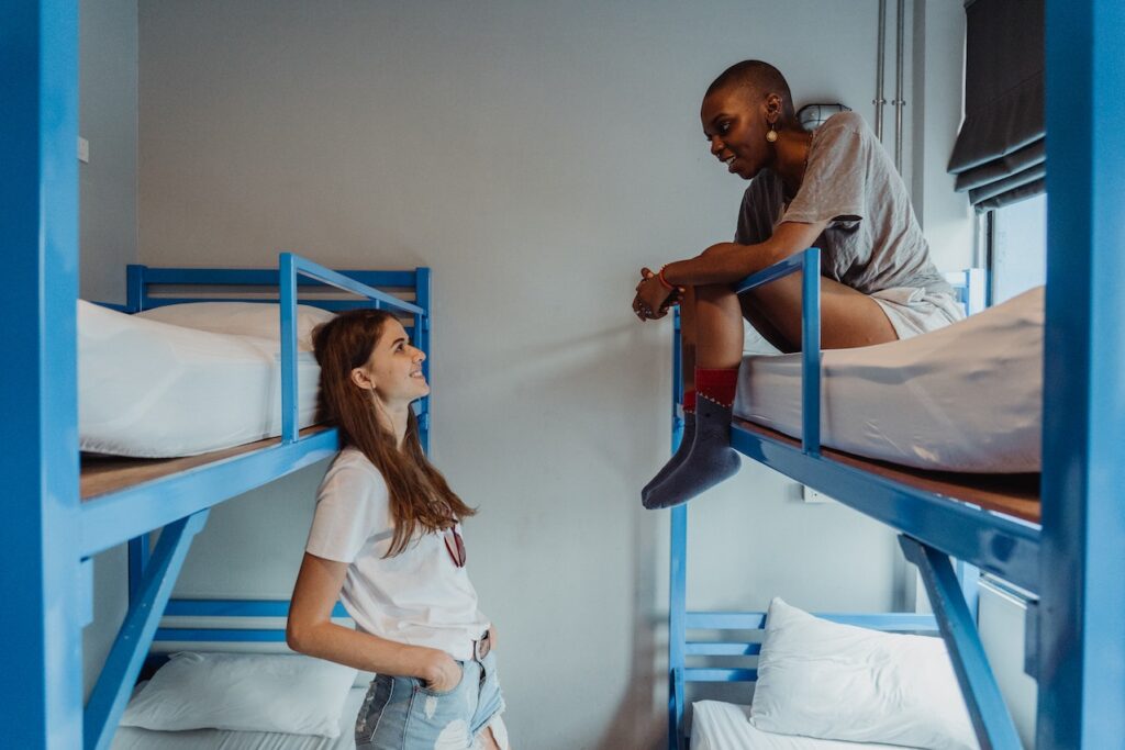 Two women talking in a room of a hostel.