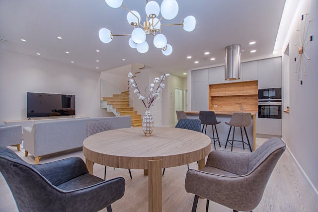 Interior of living room with wooden table, brown chairs, and a big white chandelier