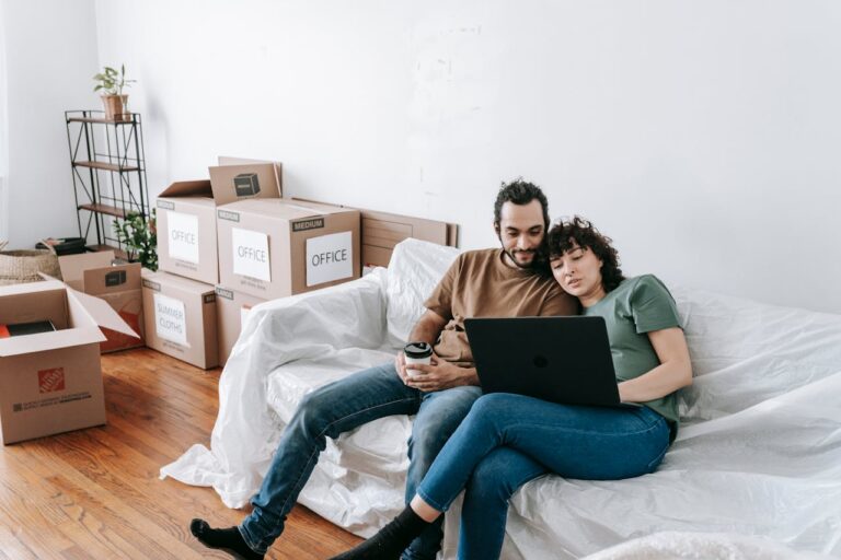 Couple sitting on a couch and browsing on a laptop.