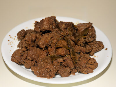 Close up of Malaysian rendang beef coated in thick coconut spice paste.
