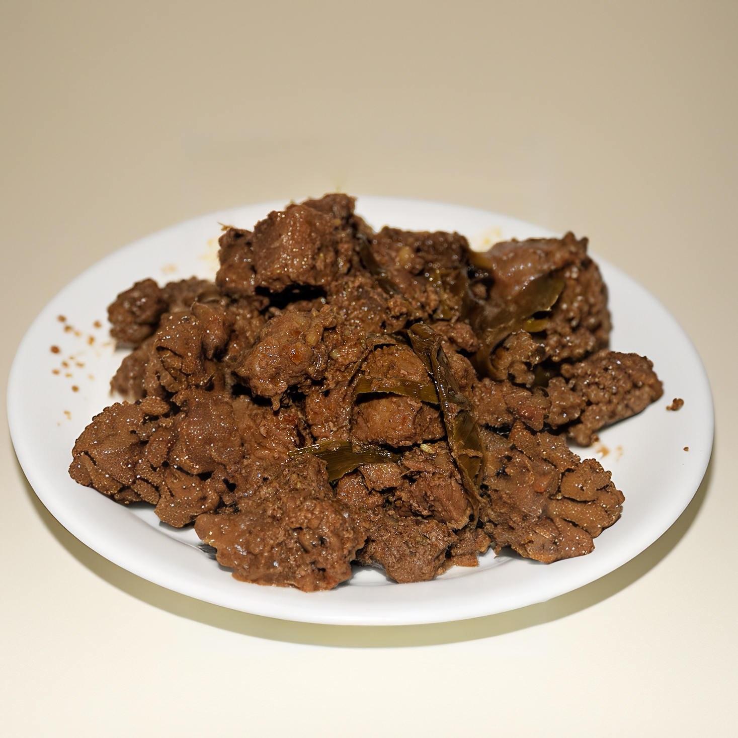 Close up of Malaysian rendang beef coated in thick coconut spice paste.