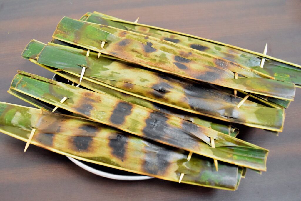 Grilled otak otak parcels wrapped in banana leaves.