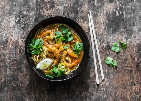 A bowl of laksa curry with shrimp and noodles, and some chopsticks on the side