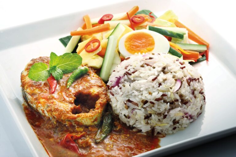 Nasi dagang with mixed rice, fish curry, cucumber, carrot and pineapple acar and boiled egg