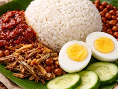 Traditional Malaysian nasi lemak plate with cucumber and sambal plus peanuts and a boiled egg. A typical breakfast dish in Malaysia.