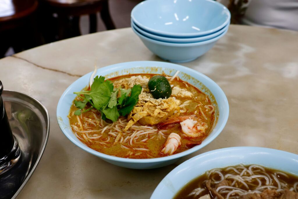 A blue bowl of curry laksa with shrimp and cilantro