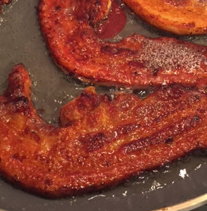Dutch speklappen pork belly slices browning in a skillet.
