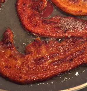 Dutch speklappen pork belly slices browning in a skillet.