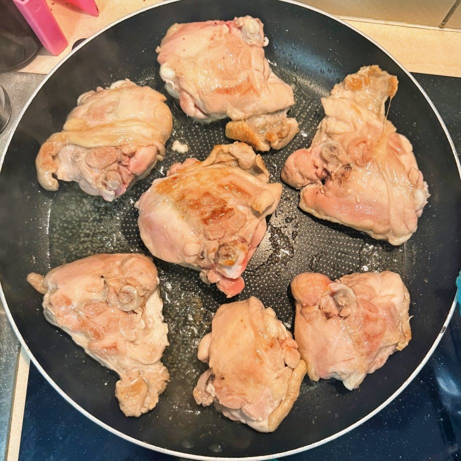 Chicken thighs beginning to brown in a skillet.