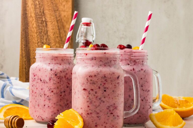 three cranberry and orange Christmas smoothies in glass mugs