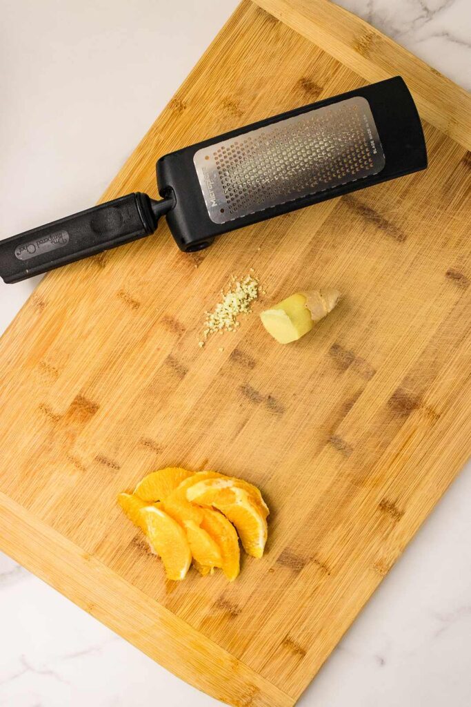 fresh ginger being grated beside orange segments