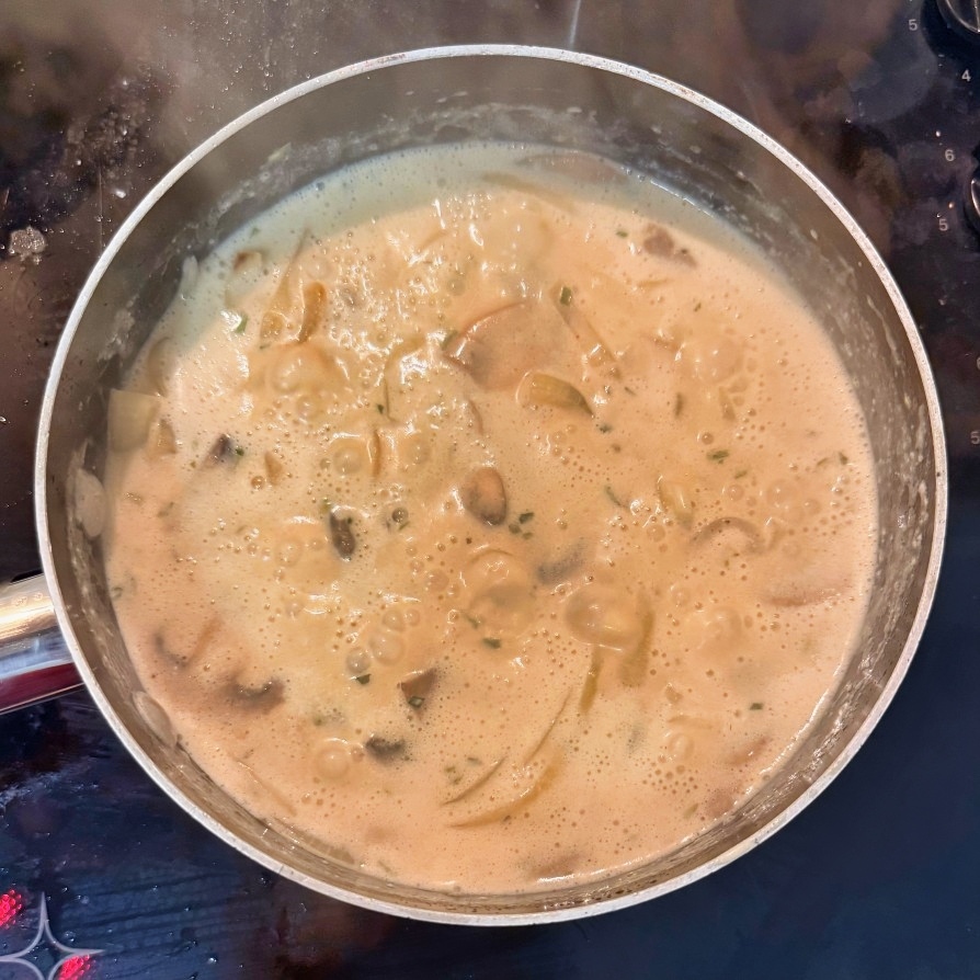 Creamy mushroom and onion sauce bubbling in a saucepan.