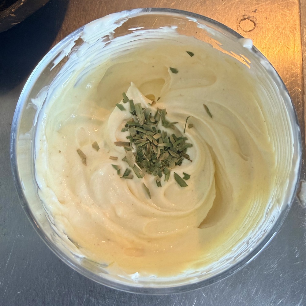 Crème fraîche topped with dried tarragon in a glass bowl.